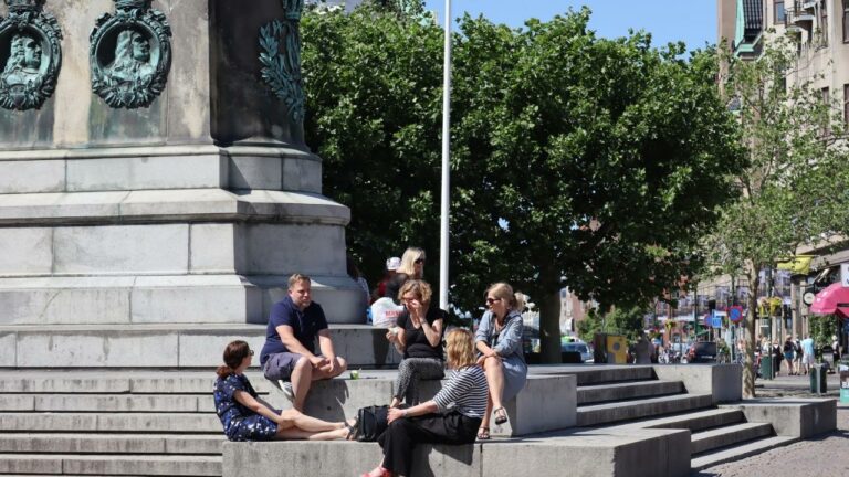 sex personer sitter på en staty i vårsolen